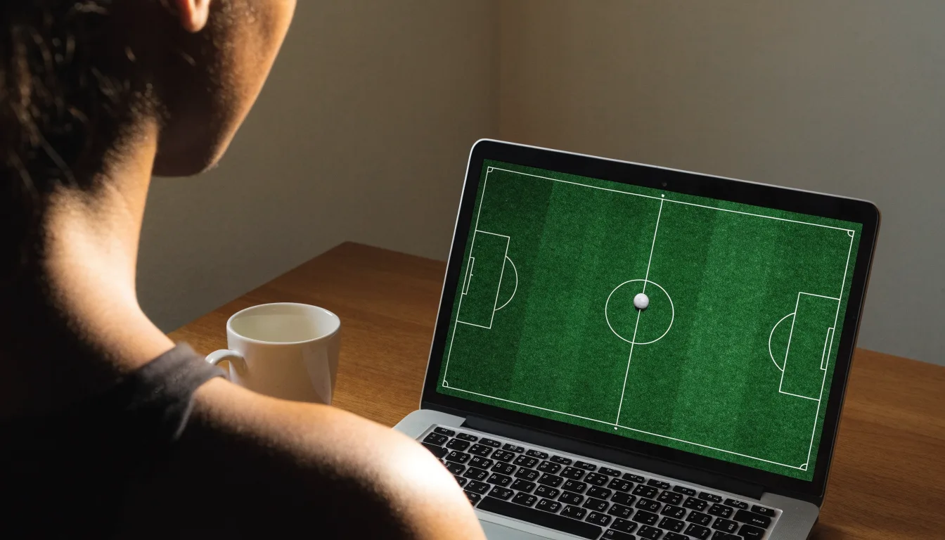 Ein Fußball liegt in der Mitte eines leeren Rasenplatzes, am Horizont färbt sich der Himmel orange.